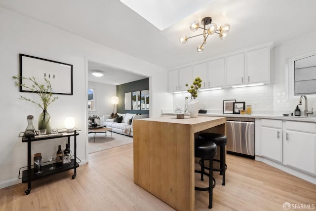 kitchen with a sink, tasteful backsplash, stainless steel dishwasher, and light countertops