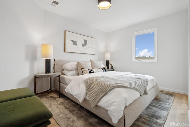 bedroom featuring visible vents, baseboards, and wood finished floors