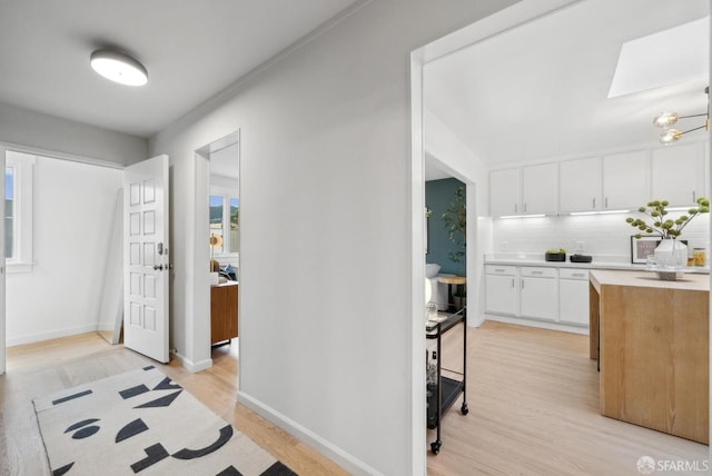 entrance foyer with a skylight, baseboards, and light wood-type flooring