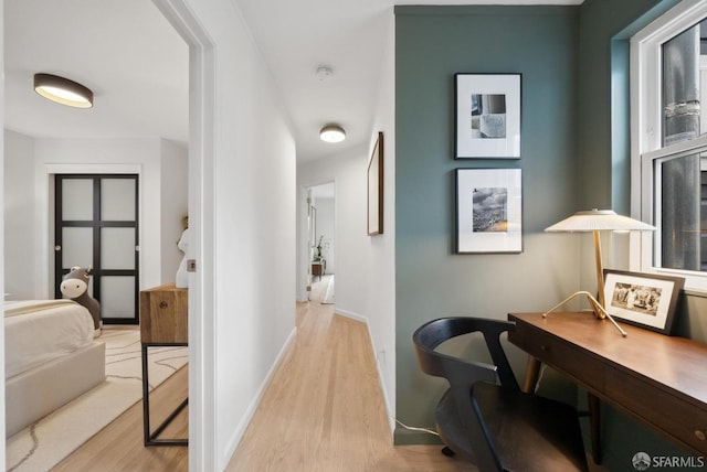 corridor with light wood-style flooring and baseboards