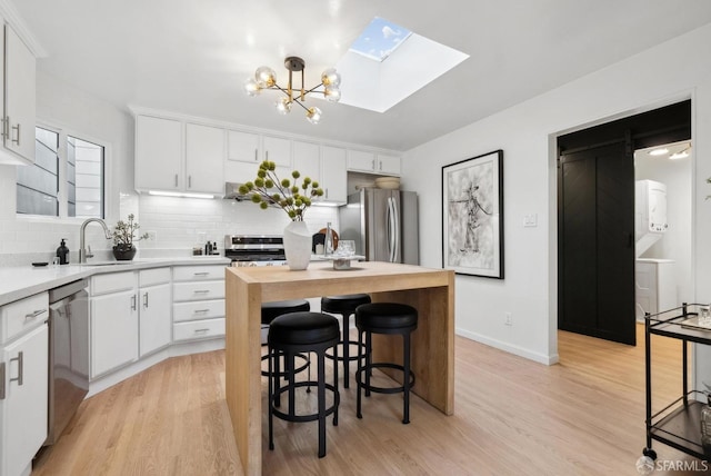 kitchen featuring a sink, wood counters, a kitchen island, stainless steel appliances, and a skylight