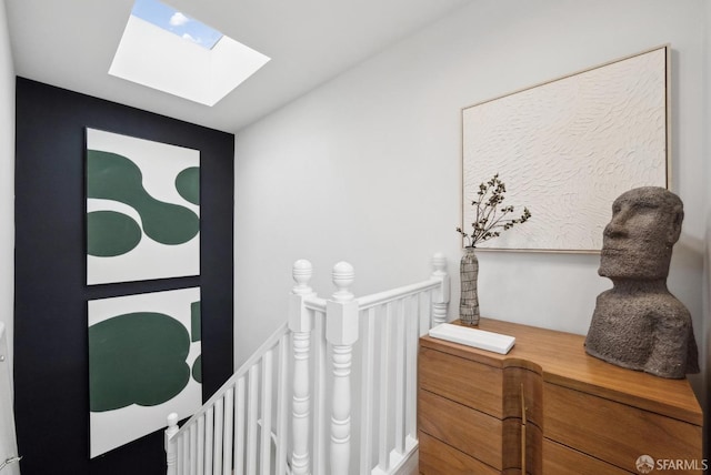 corridor featuring an upstairs landing and a skylight