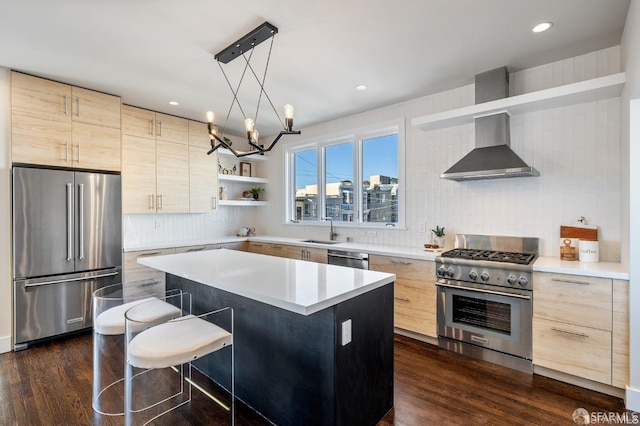 kitchen with hanging light fixtures, a kitchen island, high end appliances, a kitchen bar, and wall chimney exhaust hood