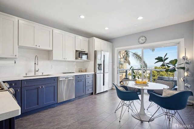 kitchen featuring stainless steel appliances, a sink, light countertops, blue cabinetry, and recessed lighting