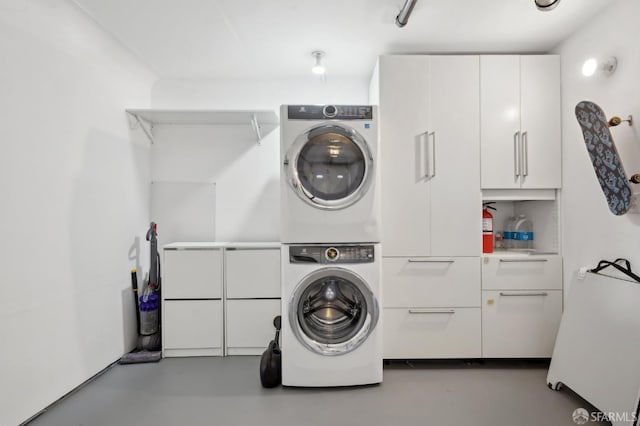 clothes washing area with estacked washer and dryer and cabinet space