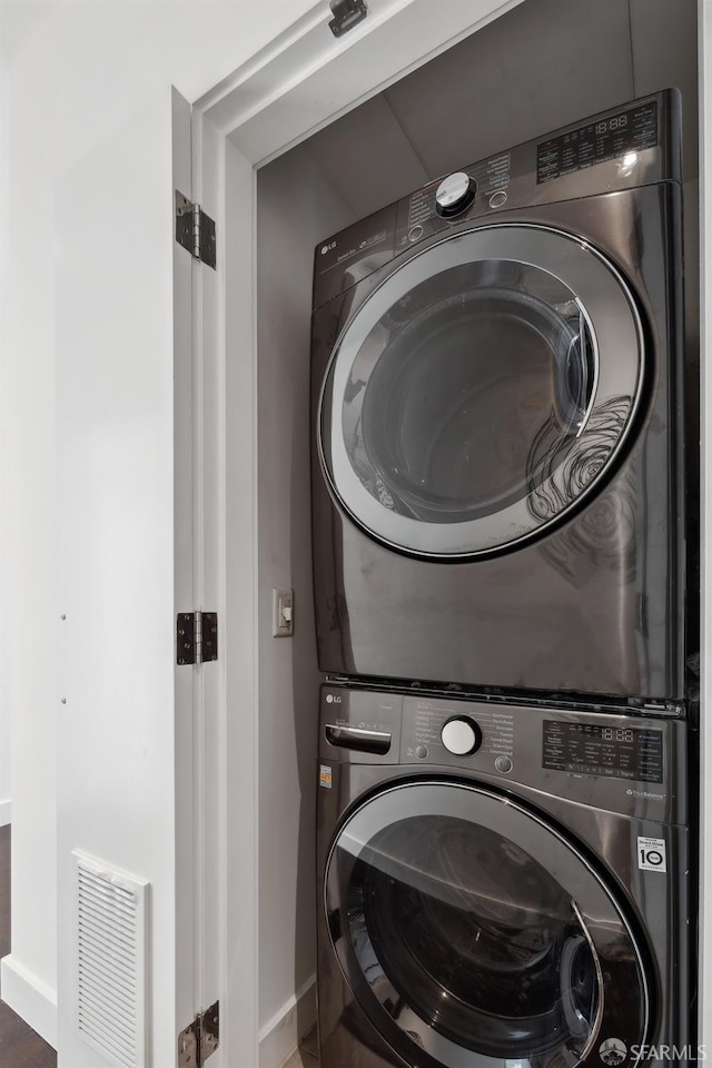 laundry area featuring laundry area, baseboards, visible vents, and stacked washer / dryer