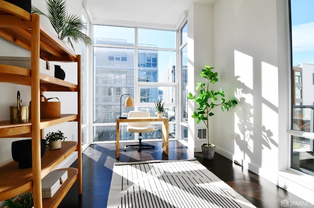 home office featuring baseboards, wood finished floors, visible vents, and floor to ceiling windows