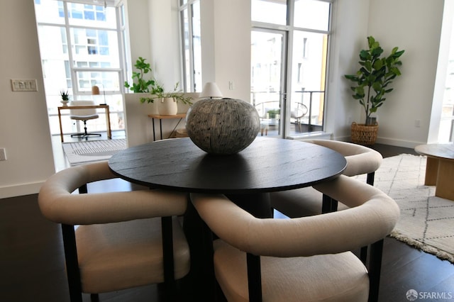 dining area with baseboards, a wall of windows, and wood finished floors