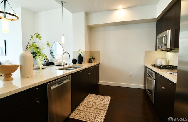 kitchen featuring baseboards, decorative backsplash, dark wood-style flooring, stainless steel appliances, and a sink