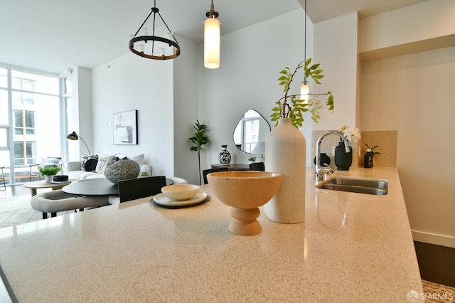 interior space featuring expansive windows, a sink, hanging light fixtures, and light stone countertops