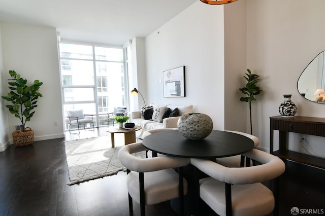 dining area featuring baseboards, a wall of windows, and wood finished floors