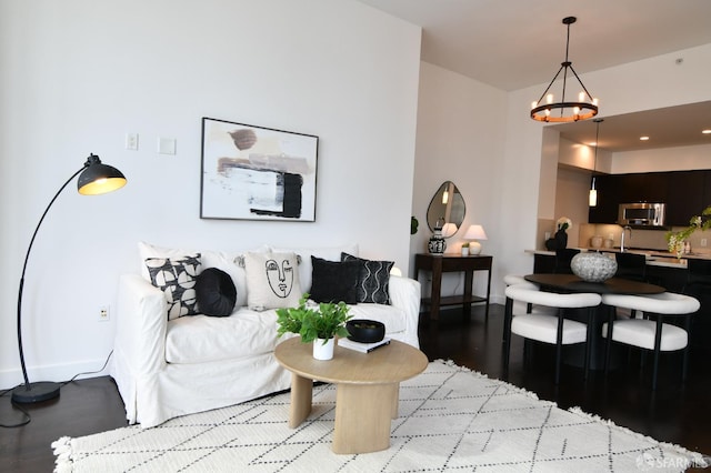 living area with a notable chandelier, baseboards, and wood finished floors