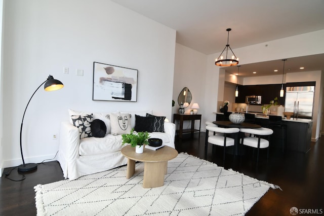 living area featuring a notable chandelier, baseboards, and wood finished floors