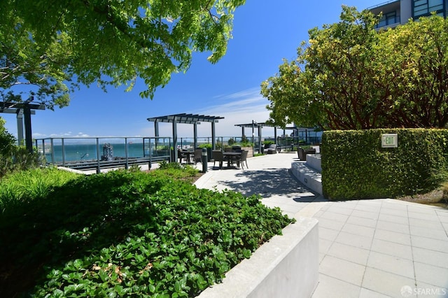 surrounding community with a water view, a patio area, and a pergola