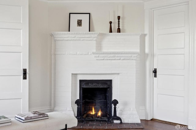 interior details featuring a brick fireplace, ornamental molding, and hardwood / wood-style flooring