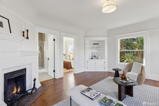 living room with built in shelves, dark hardwood / wood-style flooring, and a fireplace