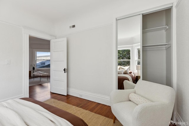 bedroom with a closet, dark hardwood / wood-style floors, and multiple windows