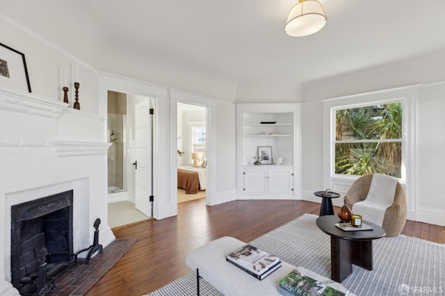 living room featuring built in features, dark hardwood / wood-style flooring, and a brick fireplace