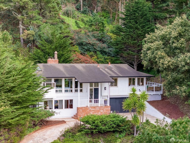 bi-level home featuring a shingled roof and a chimney