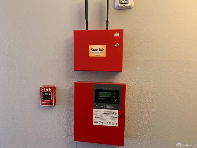 details featuring a fire alarm and a textured wall