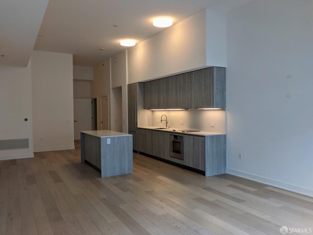 kitchen with a kitchen island, oven, sink, and light hardwood / wood-style flooring