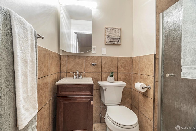 bathroom with vanity, toilet, an enclosed shower, and tile walls