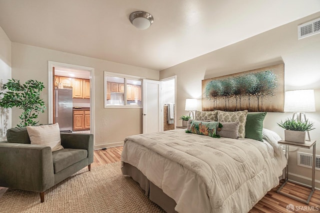 bedroom featuring stainless steel refrigerator and light hardwood / wood-style floors