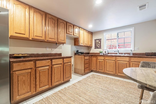 kitchen featuring sink, light tile patterned floors, and stainless steel refrigerator