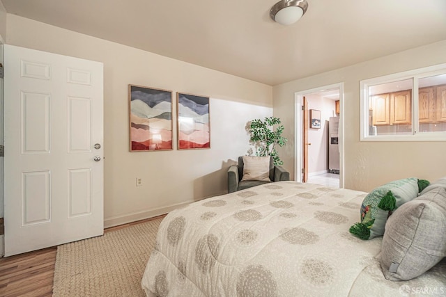 bedroom with wood-type flooring and stainless steel fridge with ice dispenser