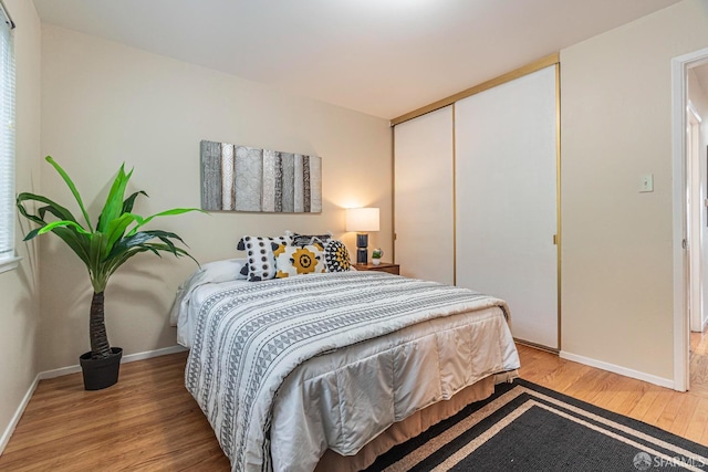 bedroom with light hardwood / wood-style floors and a closet