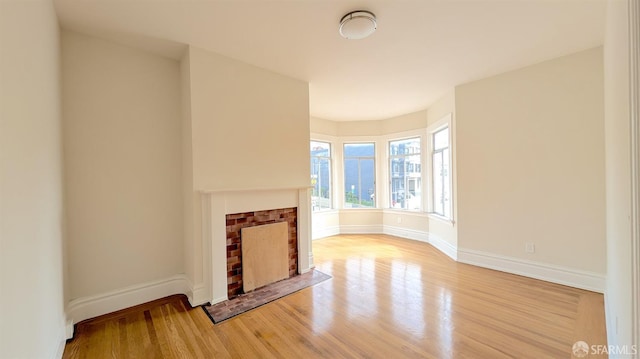 unfurnished living room with light wood finished floors, a fireplace, and baseboards