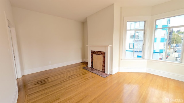 unfurnished living room featuring a fireplace, light wood-style flooring, and baseboards