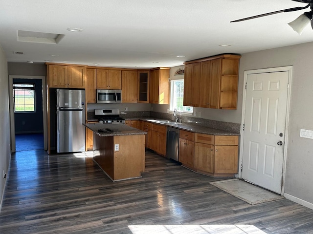 kitchen with sink, stainless steel appliances, a center island, a wealth of natural light, and dark hardwood / wood-style flooring