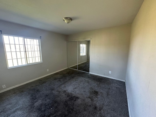 unfurnished bedroom featuring a closet and dark colored carpet