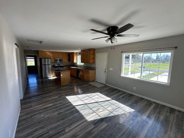 kitchen with appliances with stainless steel finishes, a center island, sink, and dark hardwood / wood-style flooring