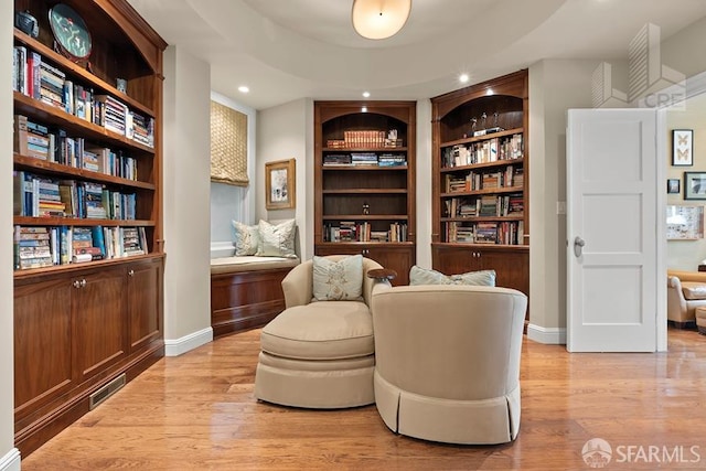 living area with light wood-type flooring and built in features