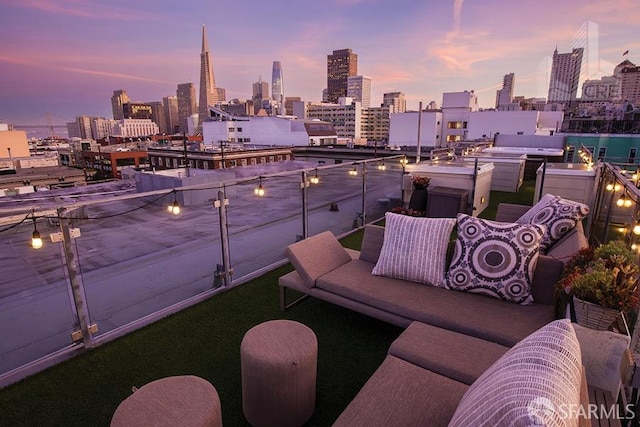 balcony at dusk with an outdoor hangout area and a grill