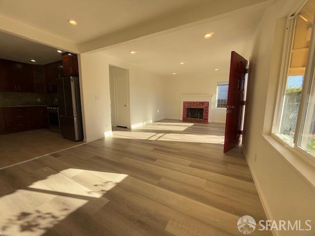 unfurnished living room with a brick fireplace and light wood-type flooring