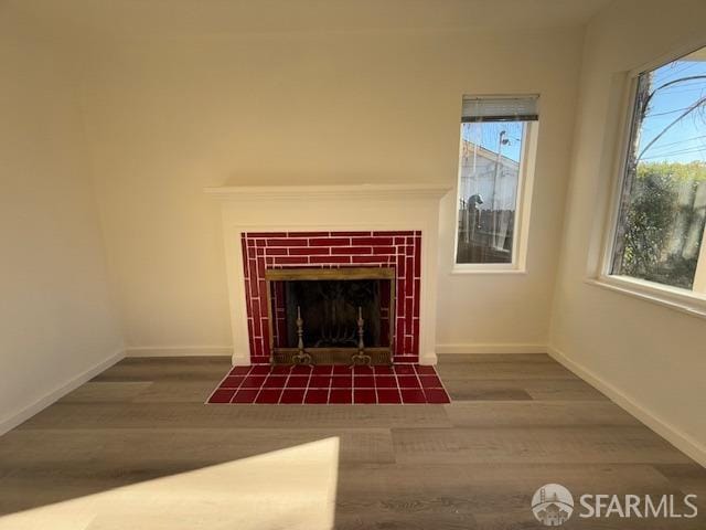 unfurnished living room with a fireplace, dark wood-type flooring, and a wealth of natural light