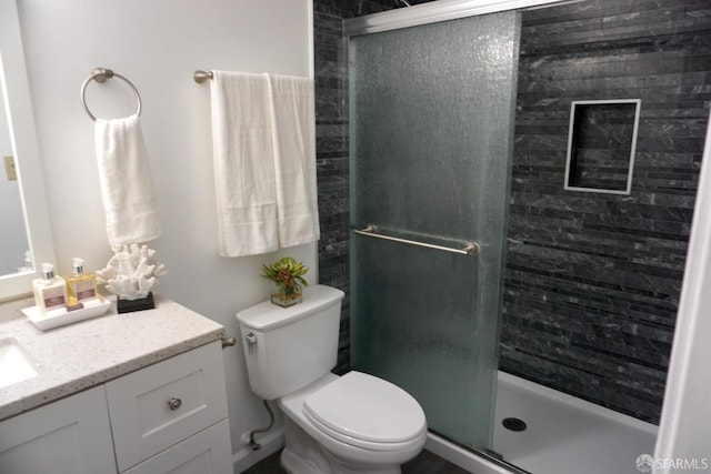 bathroom featuring toilet, a stall shower, and vanity