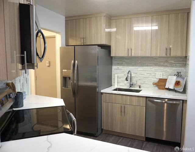 kitchen with light brown cabinets, a sink, backsplash, stainless steel appliances, and light stone countertops