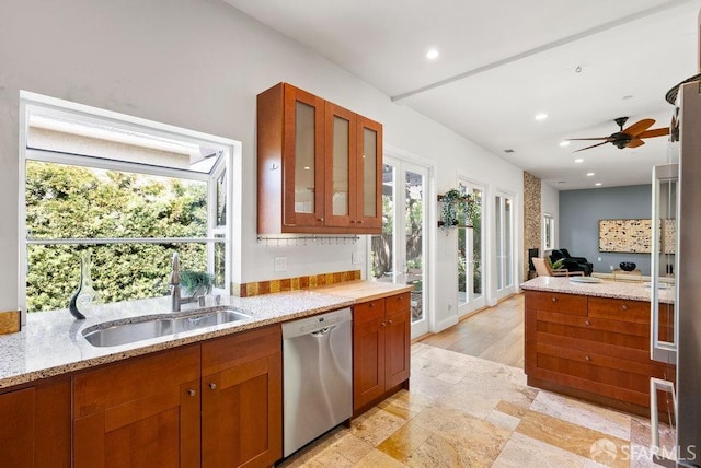 kitchen with stainless steel dishwasher, a sink, a wealth of natural light, and glass insert cabinets