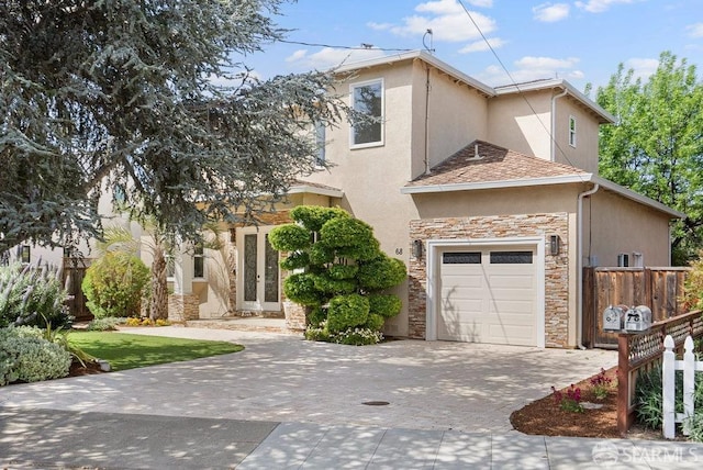 view of front of house with decorative driveway, fence, an attached garage, stone siding, and stucco siding
