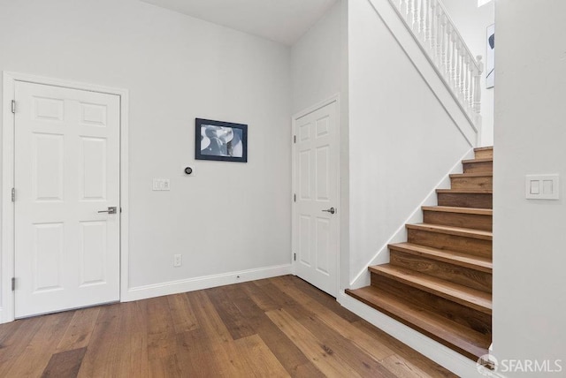 entrance foyer featuring stairs, dark wood-style flooring, and baseboards