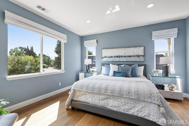bedroom featuring baseboards, recessed lighting, wood finished floors, and visible vents