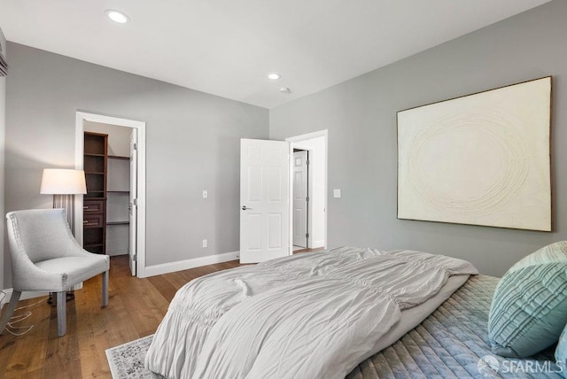 bedroom with baseboards, recessed lighting, wood finished floors, and a spacious closet