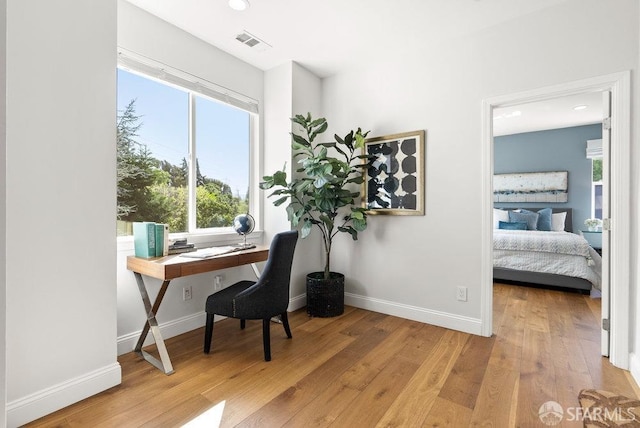 office area with light wood-style floors, baseboards, and a healthy amount of sunlight