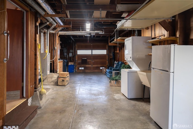 basement featuring stacked washer and clothes dryer and white fridge