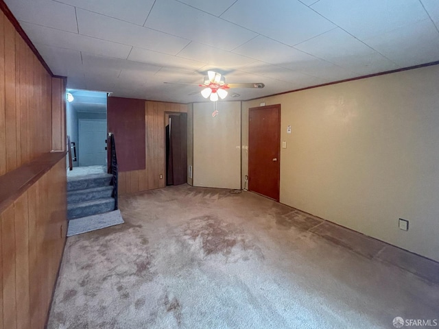 spare room featuring crown molding, light colored carpet, and wood walls