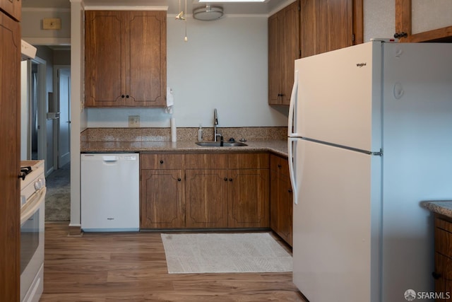 kitchen with sink, white appliances, and light hardwood / wood-style floors